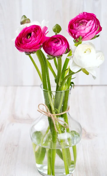 Pryskyřník květiny ve skleněné váze na dřevěný stůl — Stock fotografie