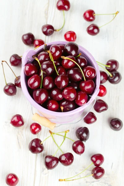 Cherries in a bucket on wooden table — Stock Photo, Image