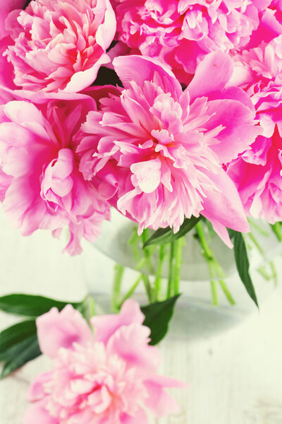 pink peonies in vase on white wooden surface