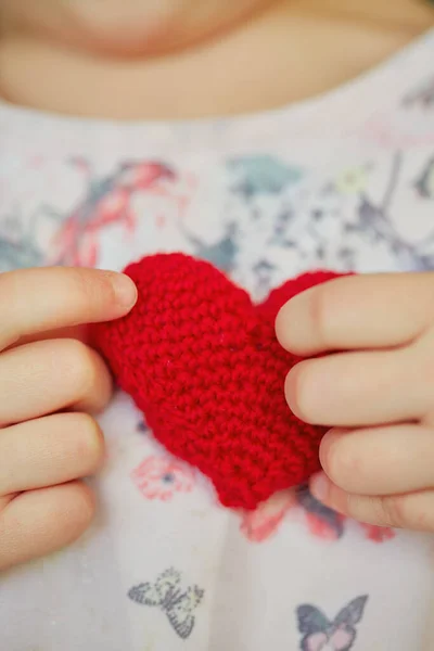 child\'s hands holding knitted heart