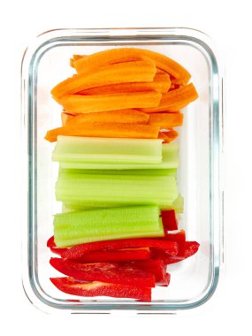 Beyaz arka planda izole edilmiş cam bir kapta havuç, kereviz ve kırmızı biber.