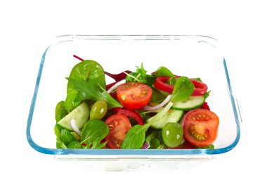 Beyaz arka planda izole edilmiş cam bir kabın içindeki sebze salatası.