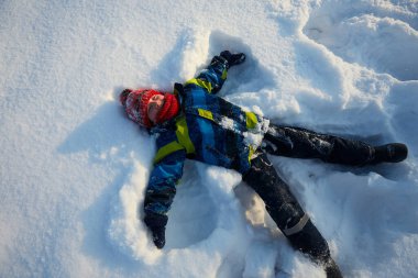Tatlı çocuk kar meleği yapıyor.