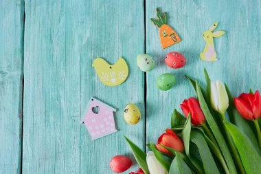Turkuaz ahşap yüzeyde laleler ve Paskalya yumurtaları
