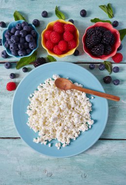 süzme peynir ve turkuaz yüzeyde taze meyveler.