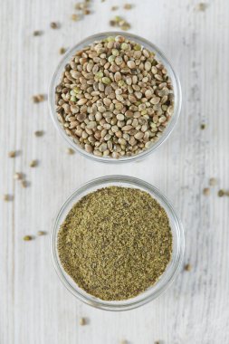 Beyaz ahşap yüzeyde bir kasede kenevir tozu.