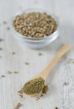 Beyaz ahşap yüzeyde bir kasede kenevir tozu.