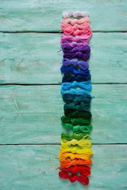 Ahşap turkuaz arka planda nakış işlemek için çok renkli iplikler.