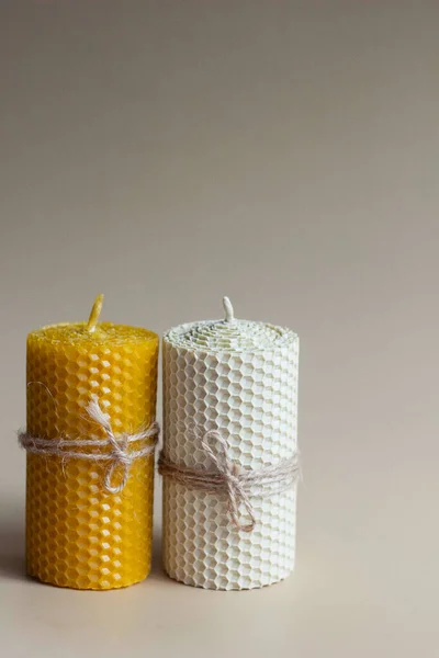 White and yellow beeswax candles with metal pot on white and brown paper