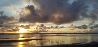 Gün batımı, Westport Deniz Feneri Eyalet Parkı, Grays Harbor, Washington yakınlarındaki bulutların arasından doğuyor.