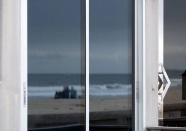 San Diego, California 'da beyaz metal çerçeveli bir pencerede Mission Beach' e gidenlerin yansımaları