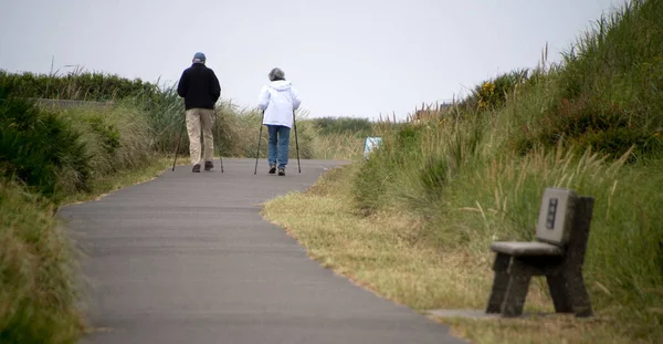 A couple of senior hikers walking away on Westport Light trail, Grays Harbor