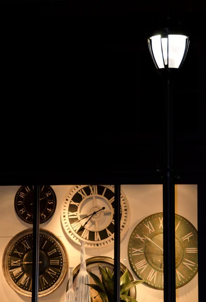 Retro wall clock in a window of shop closed for night — Stock Photo, Image