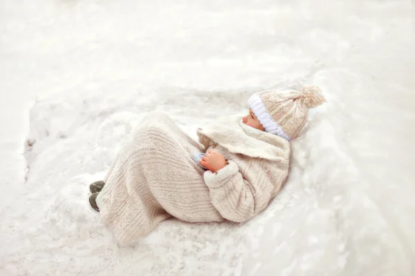 Uma menina de branco deitada na neve — Fotografia de Stock