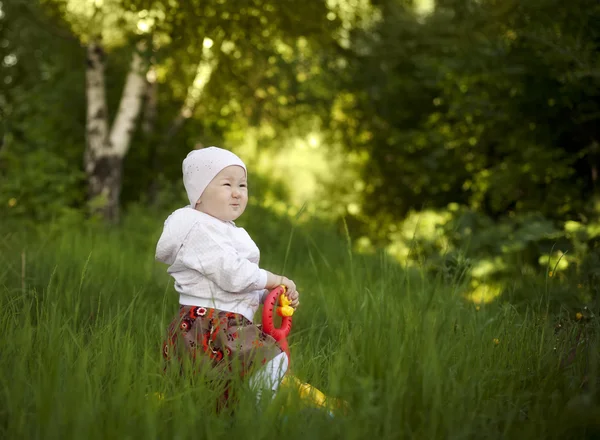 Счастливая маленькая девочка, сидящая летом — стоковое фото
