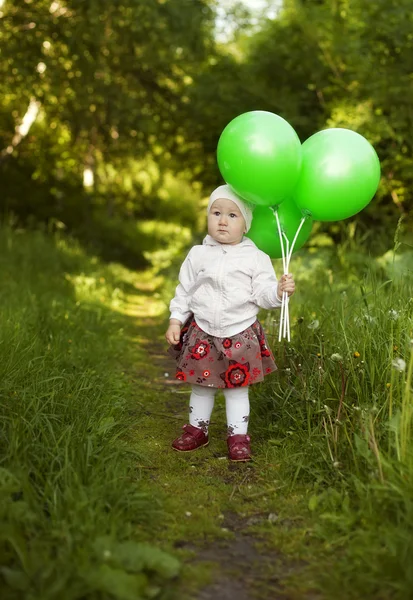 Kleines Mädchen mit grünen Luftballons — Stockfoto