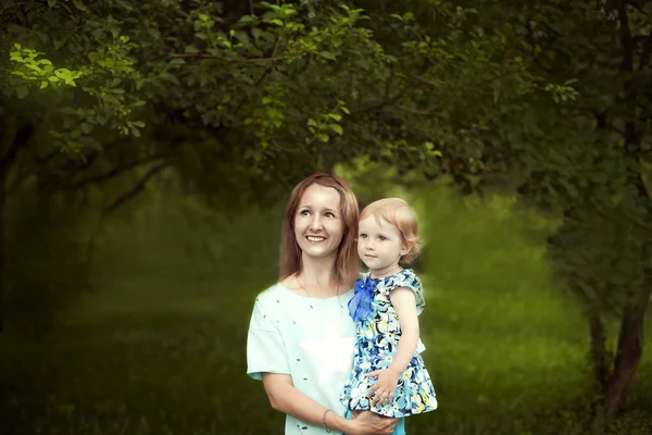 Mladá šťastná matka drží svou holčičku v náručí a s úsměvem — Stock fotografie