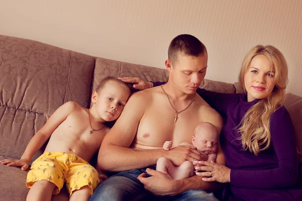 Un joven fuerte se sienta con sus hijos y esposa en casa en th —  Fotos de Stock