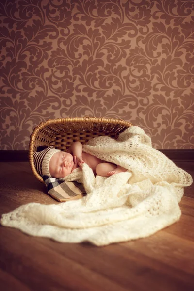 Un bebé recién nacido duerme en una habitación acogedora en una canasta, cubierta con un —  Fotos de Stock