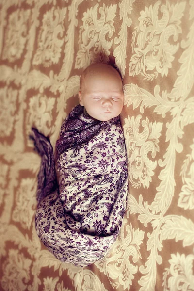 Sleeping newborn baby lying wrapped in a beautiful patterned sha — Stock Photo, Image