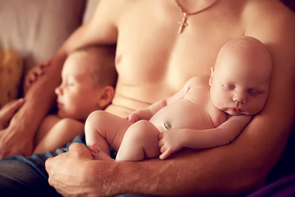 Bebê recém-nascido dormindo nos braços de um pai forte, juntamente com oi — Fotografia de Stock