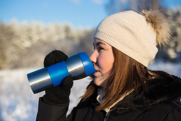 Vacker kvinna med termisk mugg i vinter skog — Stockfoto