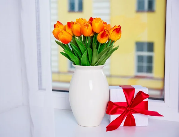 Bahar kavramı - güzel turuncu laleler ve bir pencere üzerinde hediye kutusu — Stok fotoğraf