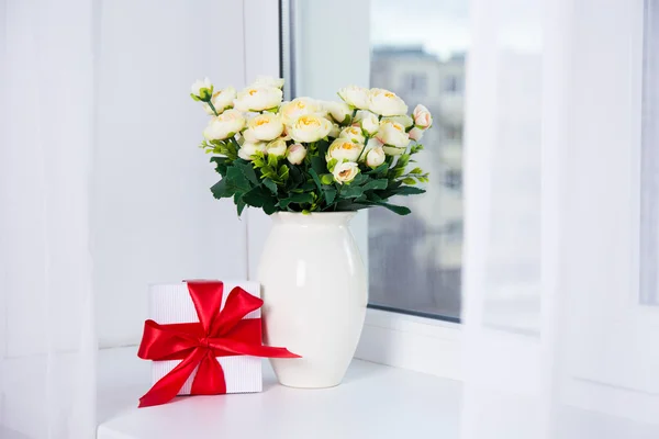 Bando de belas flores rosas e caixa de presente em um peitoril da janela — Fotografia de Stock