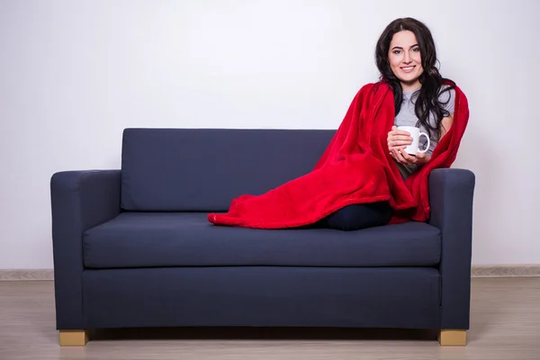 Winter-Konzept - junge Frau sitzt auf dem Sofa mit einer Tasse Tee wra — Stockfoto
