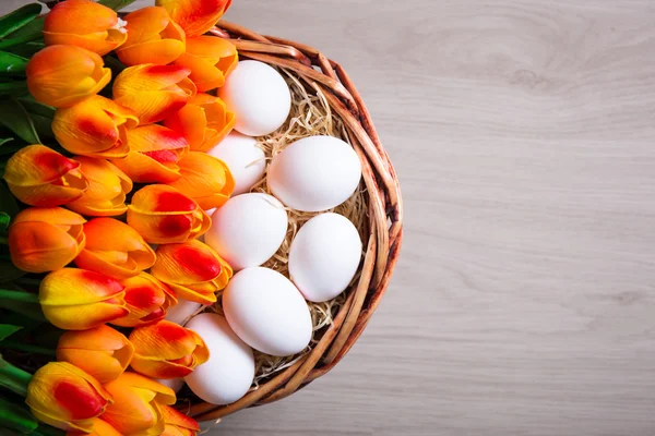 Easter concept - top view of white eggs and tulips in basket on — Stock Photo, Image