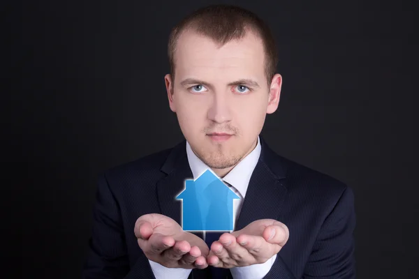 real estate concept - young man holding small house in his hands
