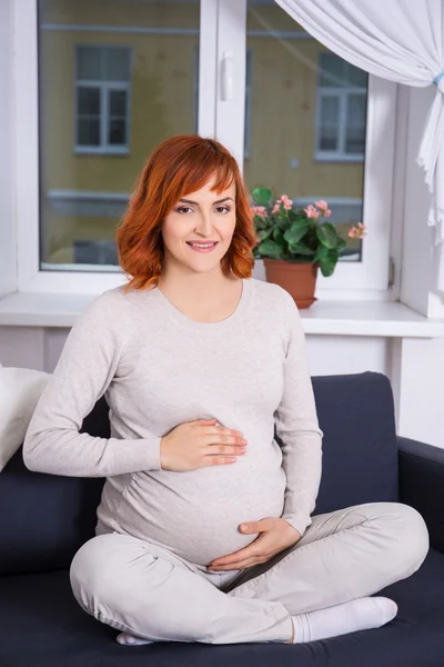 Portrét docela šťastné těhotné ženy sedí doma — Stock fotografie