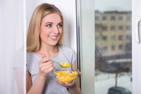 Retrato de mujer joven comer copos de maíz en casa — Foto de Stock