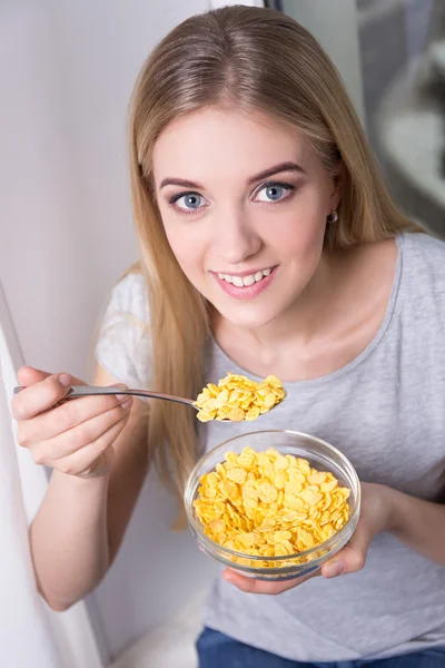 Retrato de menina bonita sorrindo, tomando café da manhã com floco de milho — Fotografia de Stock