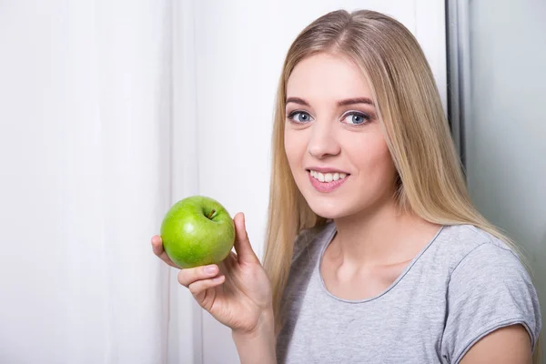 Junge Frau hält Grünen Apfel zu Hause — Stockfoto
