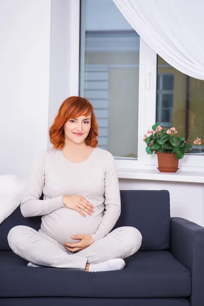 リビングの r で座っている若い妊娠中赤髪の女性の肖像画 — ストック写真