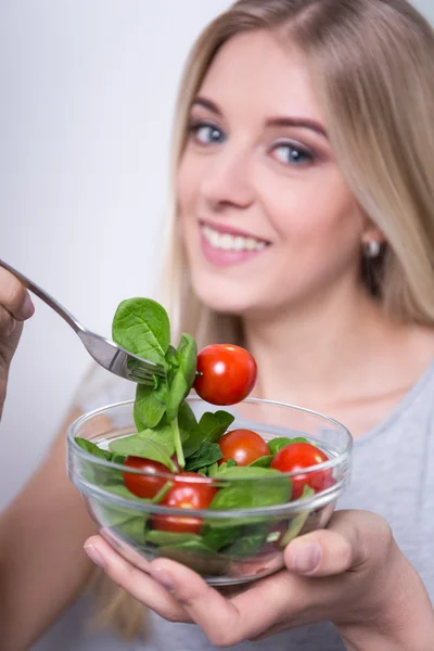 Cerca de retrato de mujer joven comer ensalada con tomate —  Fotos de Stock