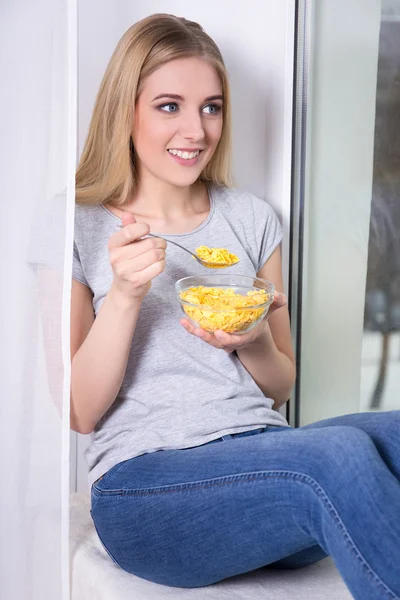 Jovem mulher comer flocos de milho em casa — Fotografia de Stock