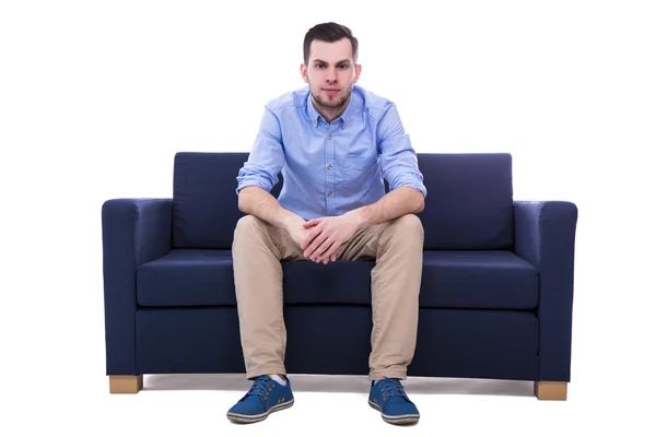 Giovane uomo bello che si siede sul sofà isolato su bianco — Foto Stock