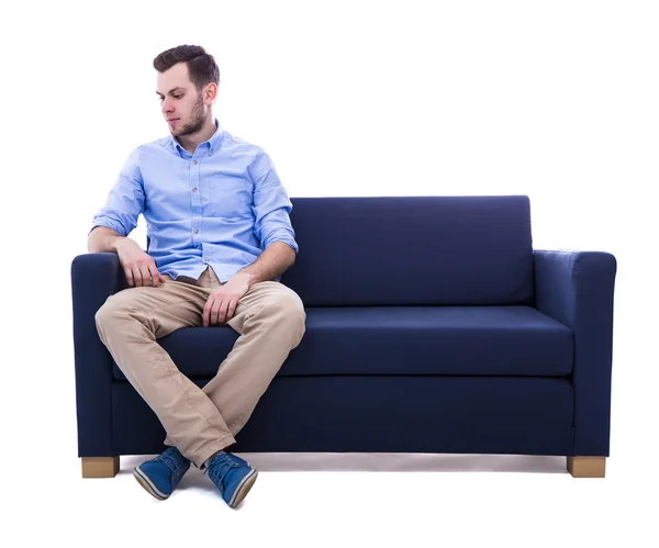 年轻男子坐在沙发上白色孤立 — 图库照片
