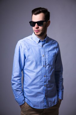 gri üzerinde poz güneş gözlüklü genç yakışıklı adam portresi
