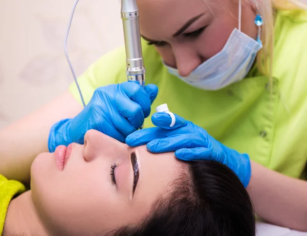 Close up portrait of cosmetologist applying permanent make up on - Stock-foto