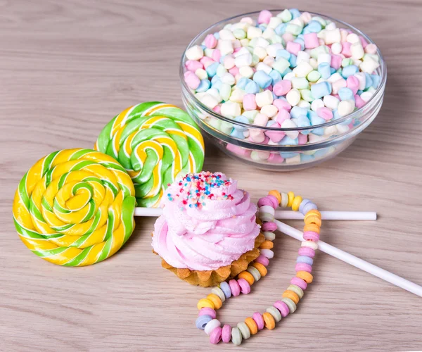 Mini marshmallows in glass bowl, candies and cup cake on wooden — Stock Photo, Image