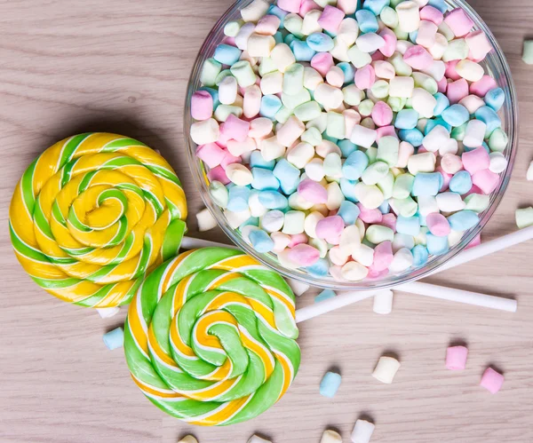 Mini marshmallows and lollipops on wooden table background — Stock Photo, Image