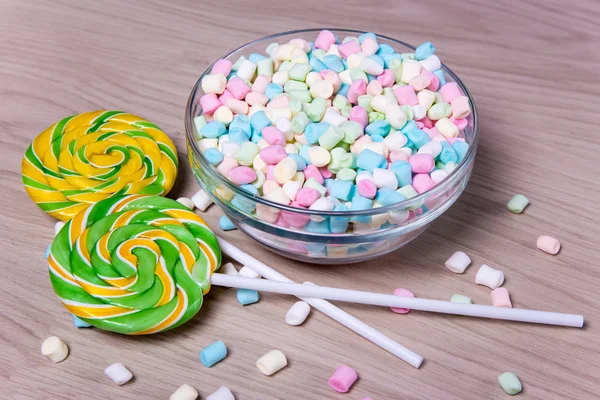 Colorful mini marshmallows and lollipops on wooden table — Stock Photo, Image