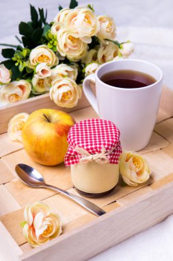 fincan çay, reçel kavanoz, elma ve çiçekler ile ahşap tepsi