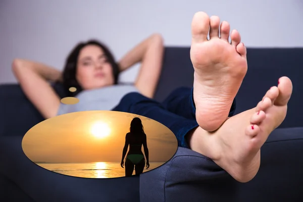Travel concept - young woman lying on sofa and dreaming about su — Stock Photo, Image