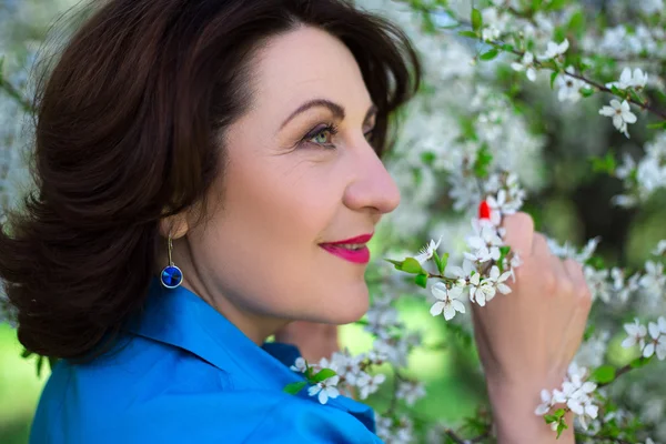 Portrait of happy middle aged woman smelling cherry tree branch — Stock Photo, Image