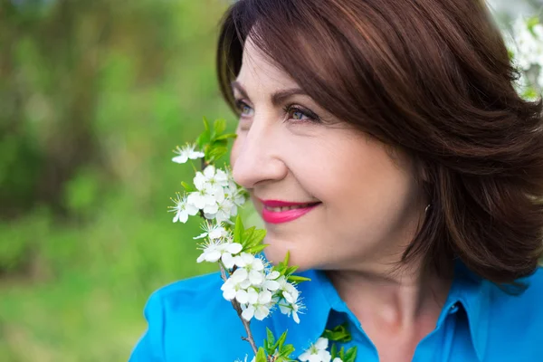 Close up portrait of middle aged woman smelling cherry tree bran — Stock Photo, Image