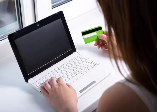 Vista de mulher usando laptop com tela em branco e segurando cr traseira — Fotografia de Stock